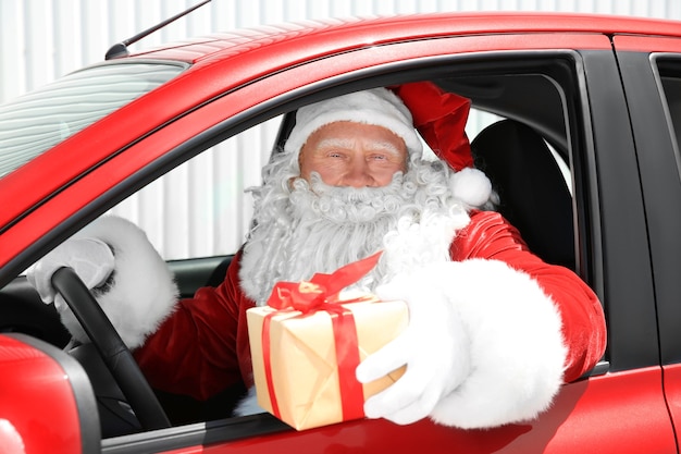 Authentieke kerstman met geschenkdoos in rode auto