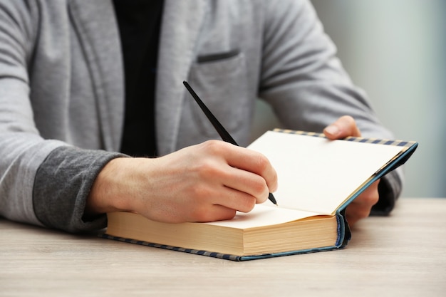 Author signing autograph in own book at wooden table