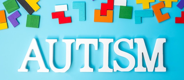 AUTISM text with colorful wood puzzle pieces geometric shape block on blue background Concepts of health Autistic Spectrum disorder and world Autism awareness day