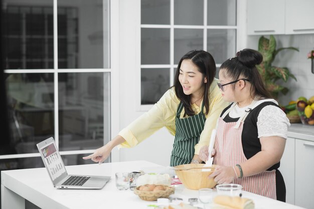 Autistic girl. Autistic girl practicing cooking with her mother in the kitchen.