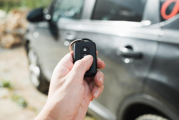 Auto alarm Close-up van menselijke hand met behulp van de afstandsbediening van de auto op de open-knop te drukken Selectieve focus op de afstandsbediening zwarte auto in bokeh