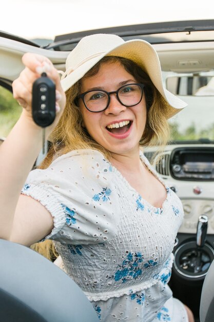 Foto auto bestuurder vrouw die lacht toont nieuwe autosleutels en auto vrouw rijden gehuurde cabrio op zomervakantie