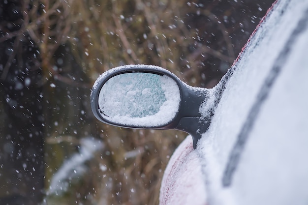 Auto buitenspiegel bedekt met verse natte sneeuw.