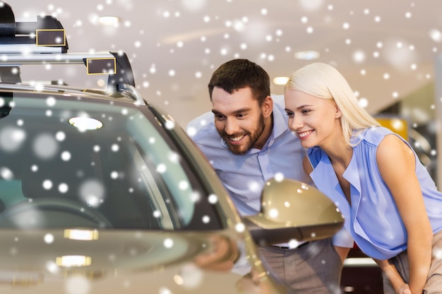 自動車ビジネス、自動車販売、消費者主義、人々 のコンセプト - 幸せなカップルが自動車ショーやサロンで雪の影響で車を購入