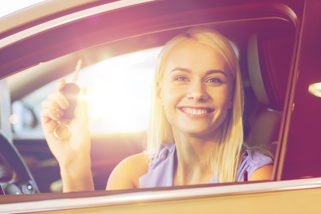 auto business, car sale, consumerism and people concept - happy woman taking car key from dealer in auto show or salon