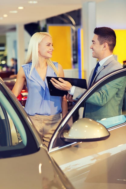 auto business, car sale, consumerism and people concept - happy woman with car dealer in auto show or salon