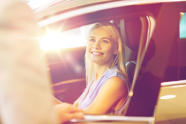 auto business, car sale, consumerism and people concept - happy woman with car dealer in auto show or salon