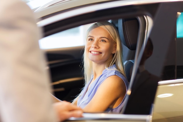 auto business, car sale, consumerism and people concept - happy woman with car dealer in auto show or salon