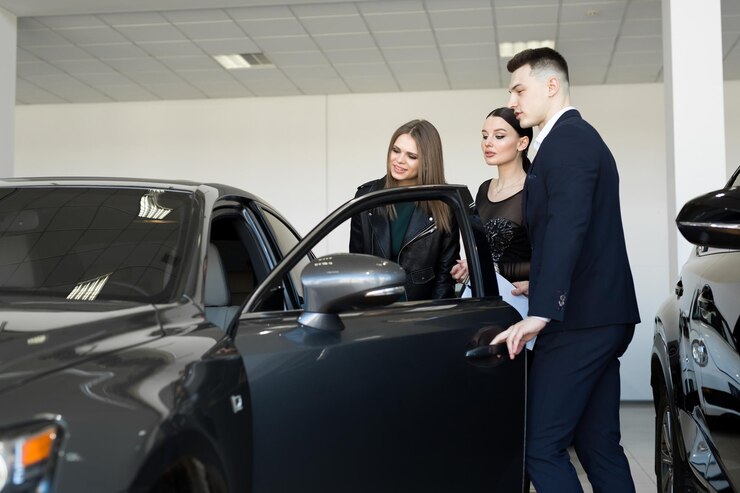 Фотография продажа авто бизнес автомобилей пара друзей девушек с автосалоном выбирают машину