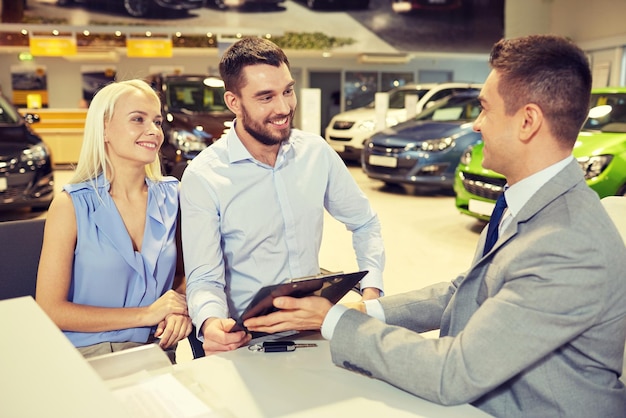 Photo auto business, sale and people concept - happy couple with dealer buying car in auto show or salon