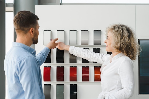 Auto dealership worker and client select the color of the car