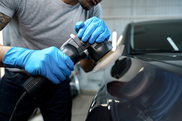 Auto detaillering mannelijke handen met orbitale polijstmachine in auto reparatiewerkplaats