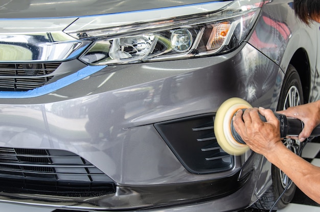 Auto detaillering - Mannelijke monteur met auto polijstmachine. Auto-industrie, auto polijsten en schilderen en reparatiewerkplaats.