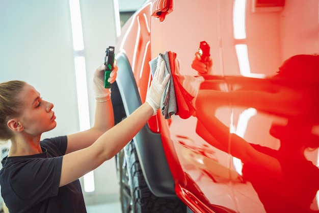 Auto detaillering werknemer die auto schoonmaakt en polijst met microvezeldoek en stofzuiger