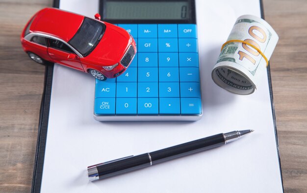 Foto auto, dollarbiljetten, rekenmachine op het bureau.