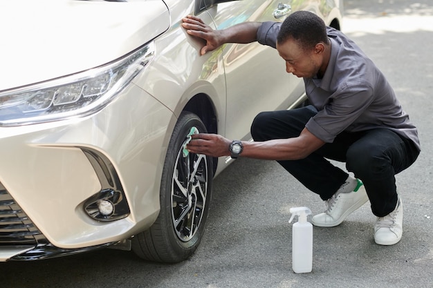 Auto-eigenaar die lichtmetalen velg schoonmaakt