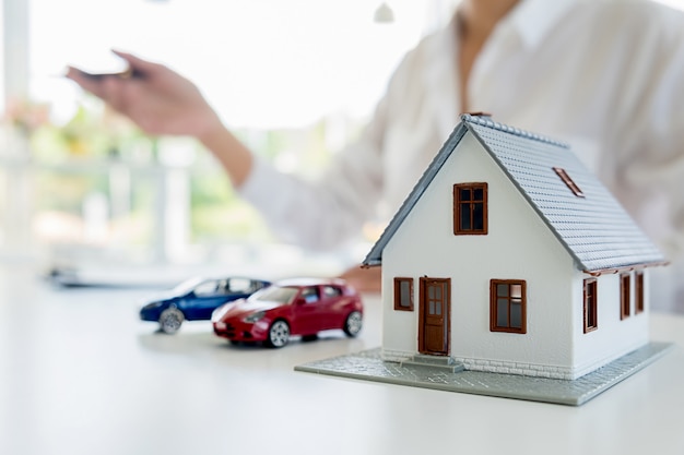 Auto en huis model met agent en klant bespreken voor contract om te kopen, krijg verzekering of lening onroerend goed of onroerend goed achtergrond.