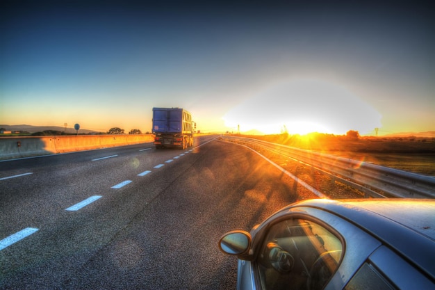 Auto en vrachtwagen op een landweg bij zonsondergang