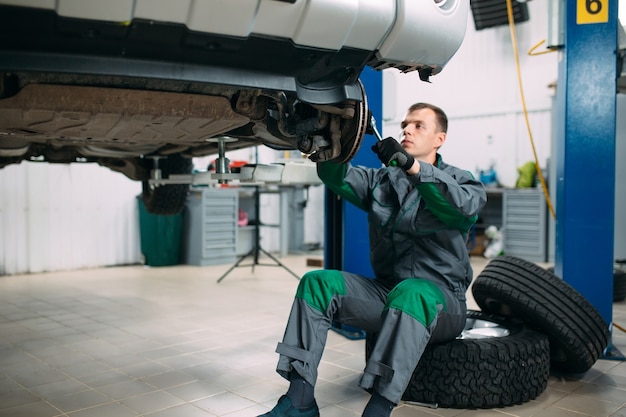 Auto gehesen in autoservice voor reparatie, arbeider repareert het wiel