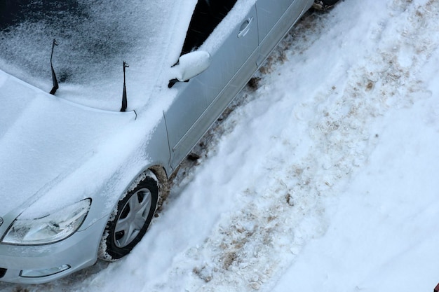 Auto geparkeerd op besneeuwde gladde weg op koude winterdag