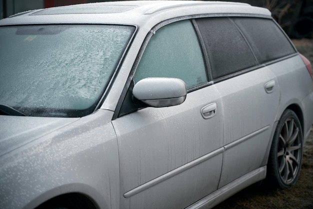 Auto is bedekt met vrieskoude ochtend met een voertuig dat 's nachts buiten geparkeerd staat