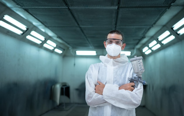 Auto mechanic in car spray room giving the spray nozzle injected into the car front bumper of car