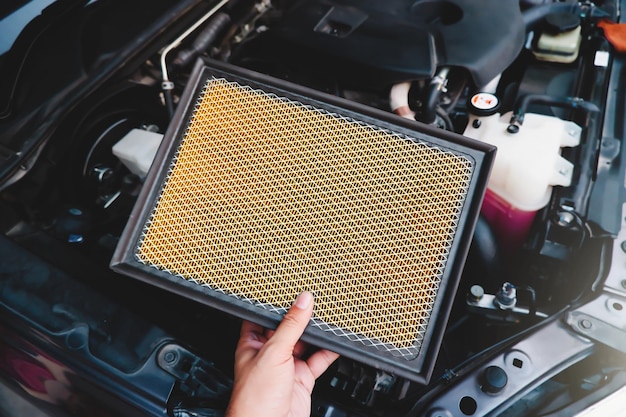 A auto mechanic carries a replacement car air filter for car engine maintenance