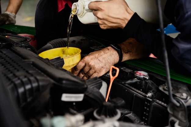 Foto macchina cambio olio meccanico. l'uomo sta cambiando l'olio del motore. sostituire l'olio del motore. sostituzione dell'olio dell'automobile. controllare il centro di servizio di riparazione di manutenzione auto.