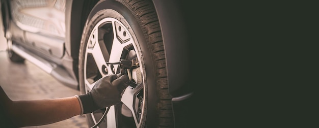 Auto mechanic checking air pressure and inflating car tires\
concept of car care service and maintenance or fix the car leaky or\
flat tire