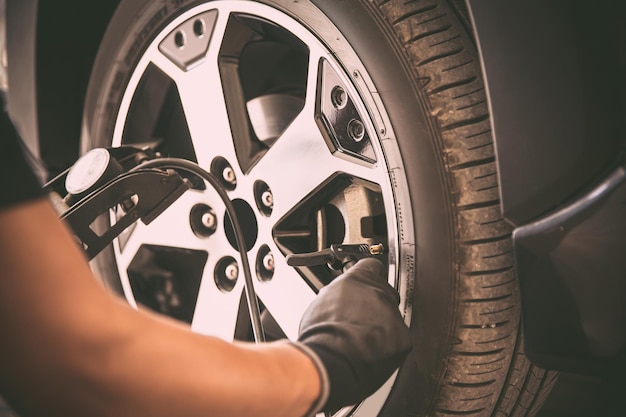 Auto mechanic checking air pressure and inflating car tires\
concept of car care service and maintenance or fix the car leaky or\
flat tire