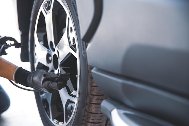 自動車整備士が空気圧をチェックし、車のタイヤを膨らませるカーケアサービスとメンテナンスの概念、または車の漏れやパンクしたタイヤの修理