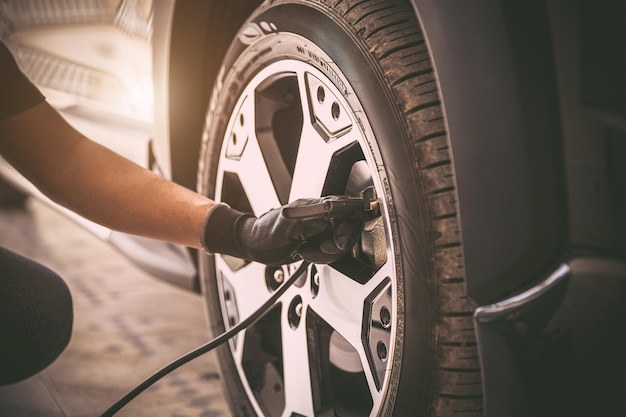 Auto mechanic checking air pressure and inflating car tires
concept of car care service and maintenance