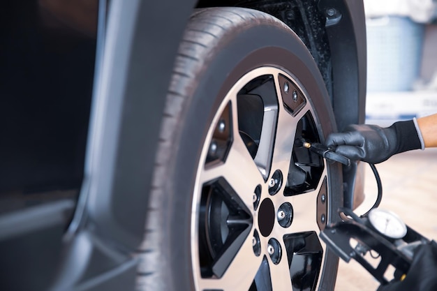 Auto mechanic checking air pressure and inflating car tires