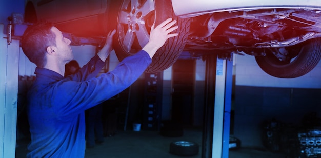 Auto mechanic examining car tire in garage