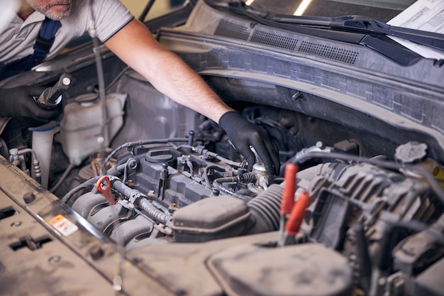 Auto mechanic fixing car engine at service station