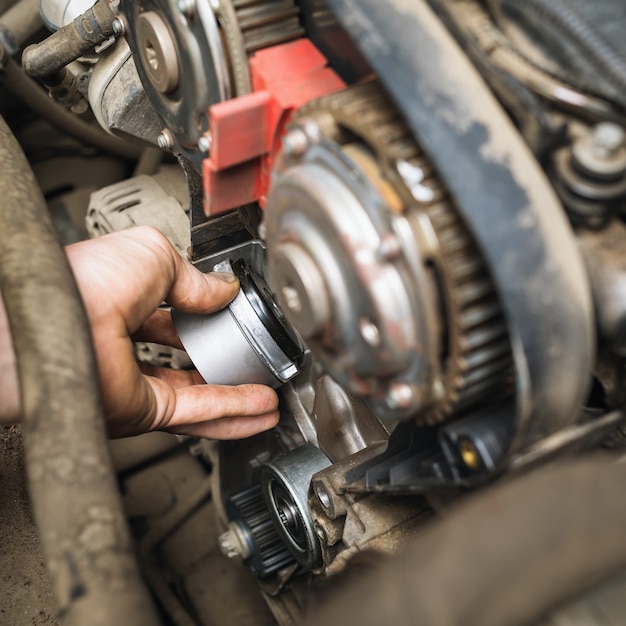 An auto mechanic installs a timing belt idler