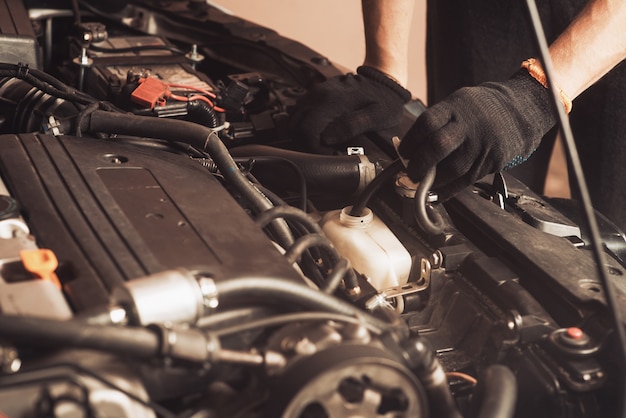 Auto mechanic repairs car. The employee carries out maintenance of the machine.