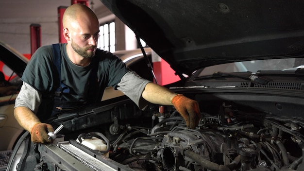 Il meccanico automobilistico ripara il primo piano di servizio dell'automobile del motore dell'automobile