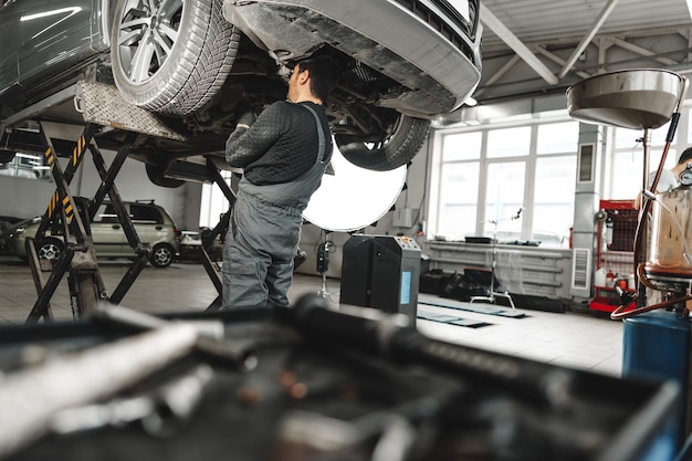 Auto mechanic repairs running gear of a car in car service