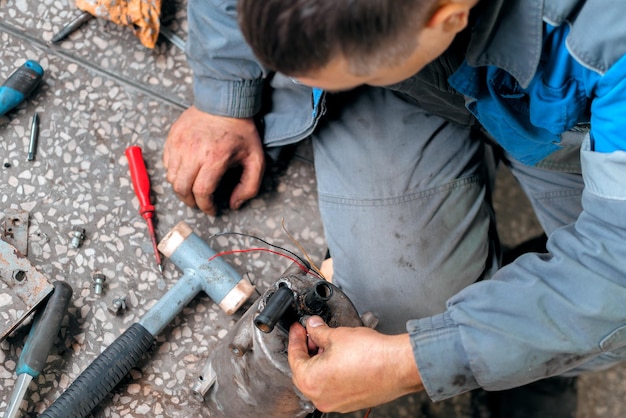 Auto mechanic repairs truck Professional repair and diagnostics of cargo tractors and equipment Mechanic in workshop considers spare parts View from top