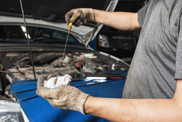 An auto mechanic at a service station checks the oil level in a car engine after changing it