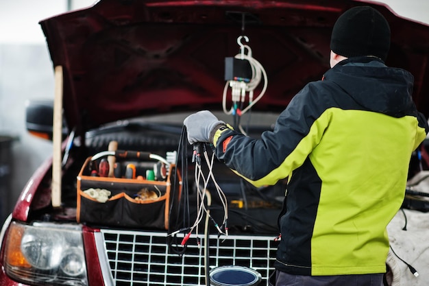 Il meccanico automobilistico imposta l'auto suv americana per la diagnostica e la configurazione nella stazione di servizio dell'officina