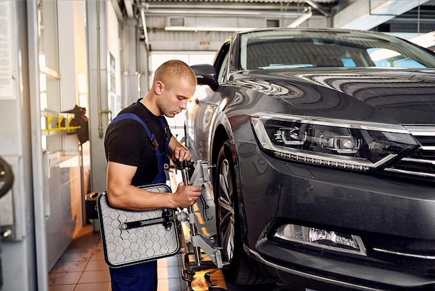 Auto mechanic sets the car for diagnostics and configuration\
collapseconvergence car wheels alignment equipment on stand in a\
repair station