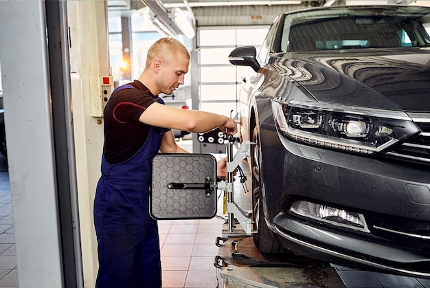 Auto mechanic sets the car for diagnostics and configuration\
collapseconvergence car wheels alignment equipment on stand in a\
repair station