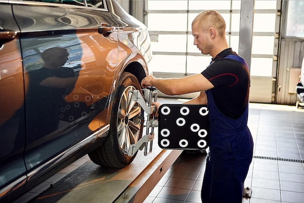 Auto mechanic sets the car for diagnostics and configuration collapseconvergence Car Wheels alignment equipment on stand in a repair station