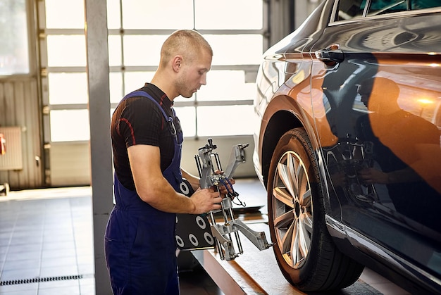 Auto mechanic sets the car for diagnostics and configuration collapseconvergence Car Wheels alignment equipment on stand in a repair station