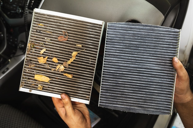 Photo an auto mechanic shows a close-up of an old and new cabin air filter for comparison