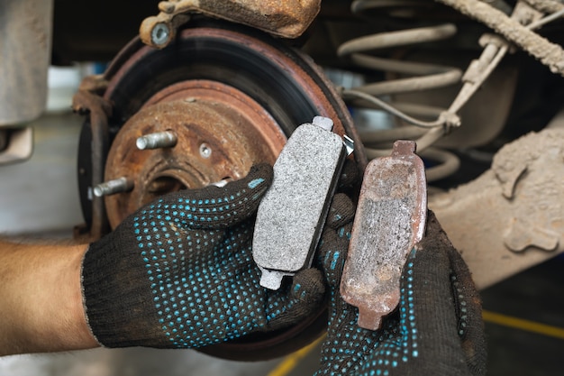 auto mechanic shows old and new brake pads