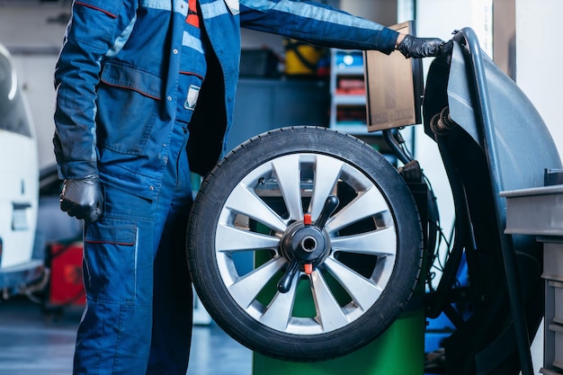 Photo auto mechanic uses tire balancing machine and turning tire