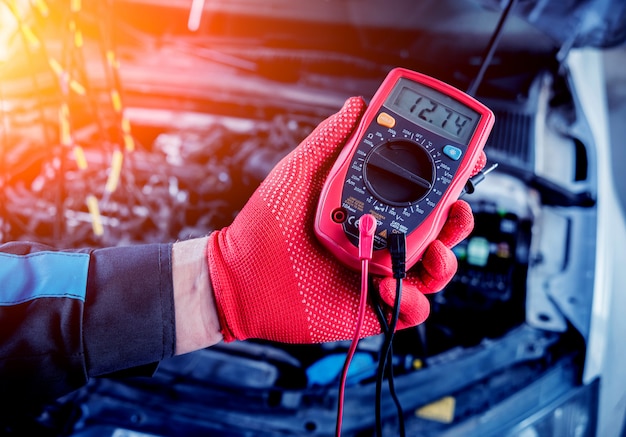 Auto mechanic uses a voltmeter to check the voltage level.